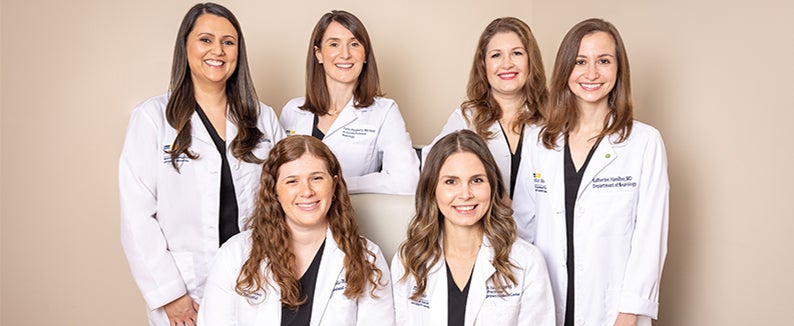 Six medical professionals stand together wearing white coats